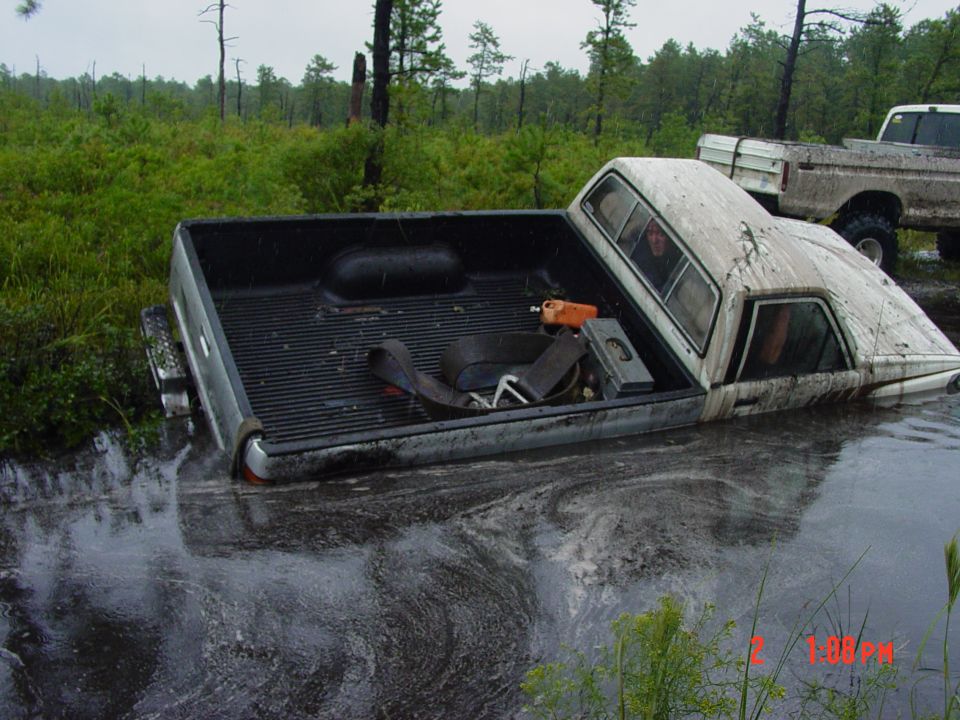 Truck stuck in murky water with another truck behind it