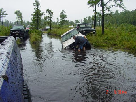 1995 Dodge 1500 - A group of trucks navigate a flooded area, with one white van partially submerged and a person attempting to free it.