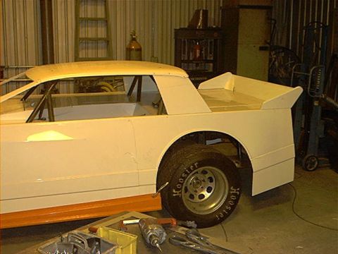 1978 Ford Bronco - A partially completed race car project sits in a workshop, showing its side profile and a Hoosier tire.