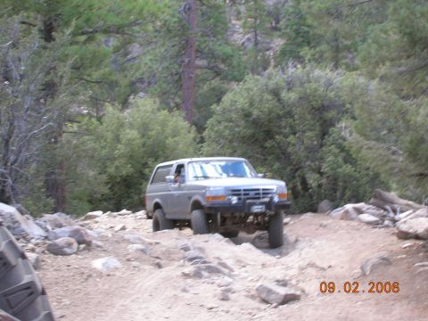 1985 Ford Bronco - This 1985 Ford Bronco navigates a challenging off-road course amidst trees and rocks.