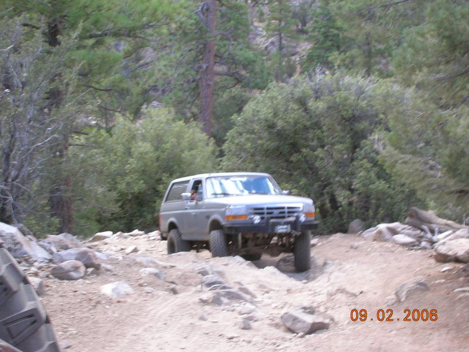 Silver 1985 Ford Bronco driving on a rocky trail
