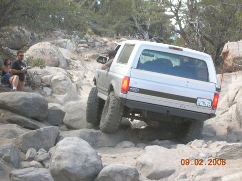 1985 Ford Bronco - A silver 1985 Ford Bronco tackles a challenging rocky terrain on an off-road adventure.