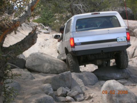 1985 Ford Bronco - 1985 Ford Bronco tackles a challenging off-road course with large rocks.