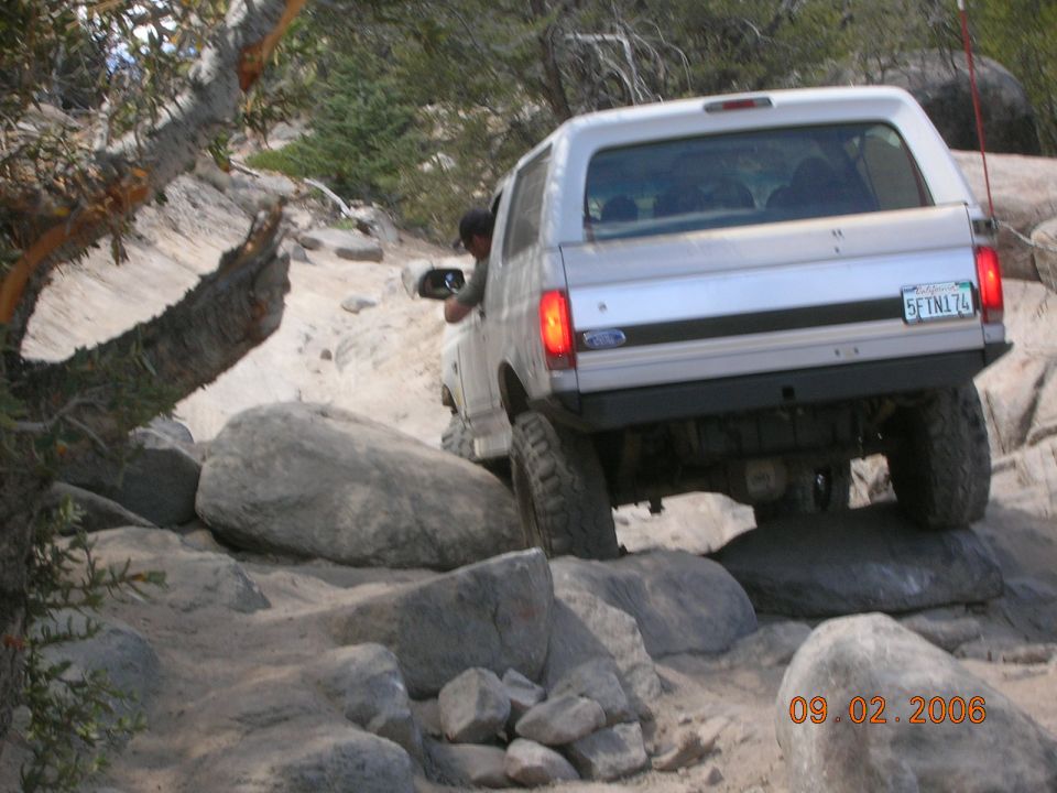 1985 Ford Bronco navigating a boulder-strewn trail, rear view. License plate 5FTN174