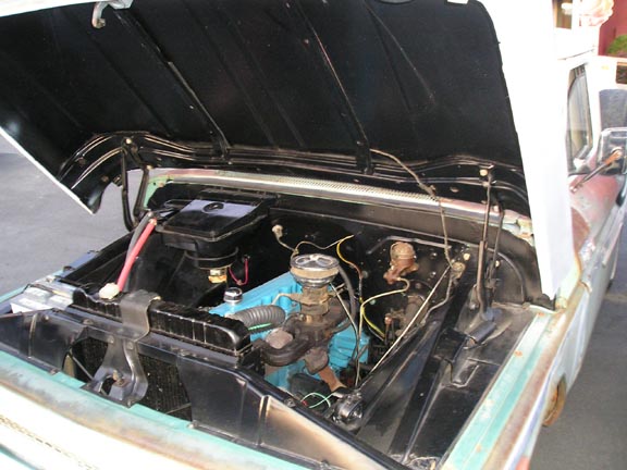 Engine bay of a classic truck with hood open. Blue engine block visible
