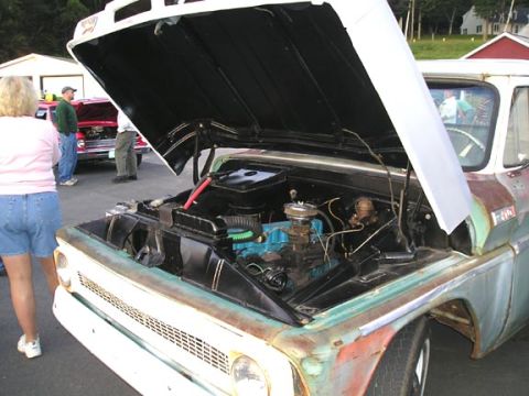 1984 Pontiac Fiero - The engine compartment of a classic pickup truck is displayed with its hood raised, revealing the engine and surrounding components.