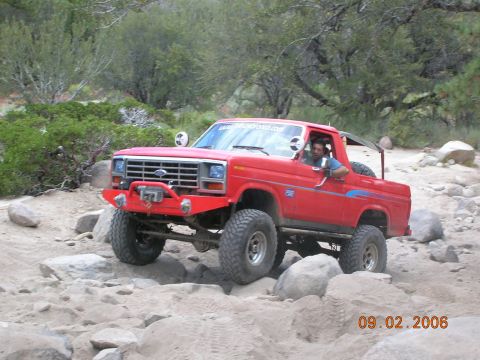 1985 Ford Bronco - A red Ford Bronco navigates a rocky, off-road trail.