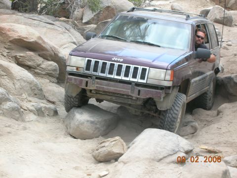 1985 Ford Bronco - A Jeep Grand Cherokee navigates a rocky off-road trail, with the date 09.02.2006 visible in the corner.