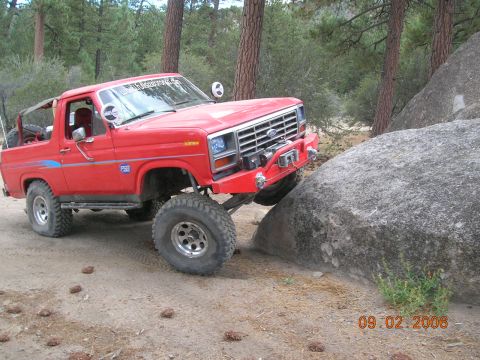 1985 Ford Bronco - This red 1985 Ford Bronco is shown navigating a rocky obstacle on an off-road trail.