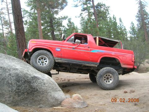 1985 Ford Bronco - This red SUV is navigating a rocky trail in a wooded area, with a date stamp indicating it was taken in 2006.