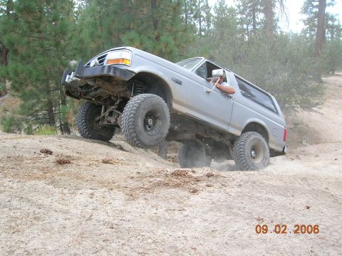 1985 Ford Bronco - This Ford Bronco is navigating a steep, sandy incline in a wooded area.