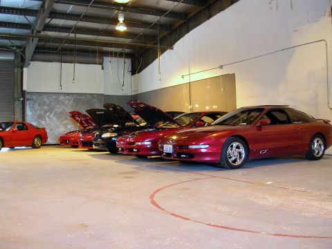 1996 Ford Probe - Several Ford Probes are lined up in a garage, most with their hoods open.