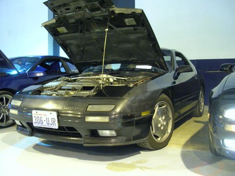 1996 Ford Probe - A black Mazda RX-7 is parked indoors with its hood open, revealing the engine bay.