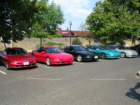 1996 Ford Probe - Several Ford Probes are parked in a lot, with a train visible in the background.