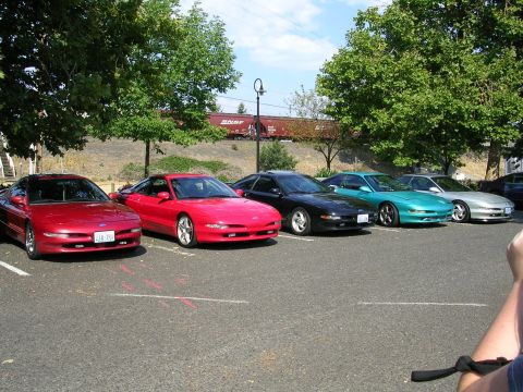 1996 Ford Probe - A lineup of Ford Probes, including a red one in the foreground, parked outdoors with trees and a train in the background.