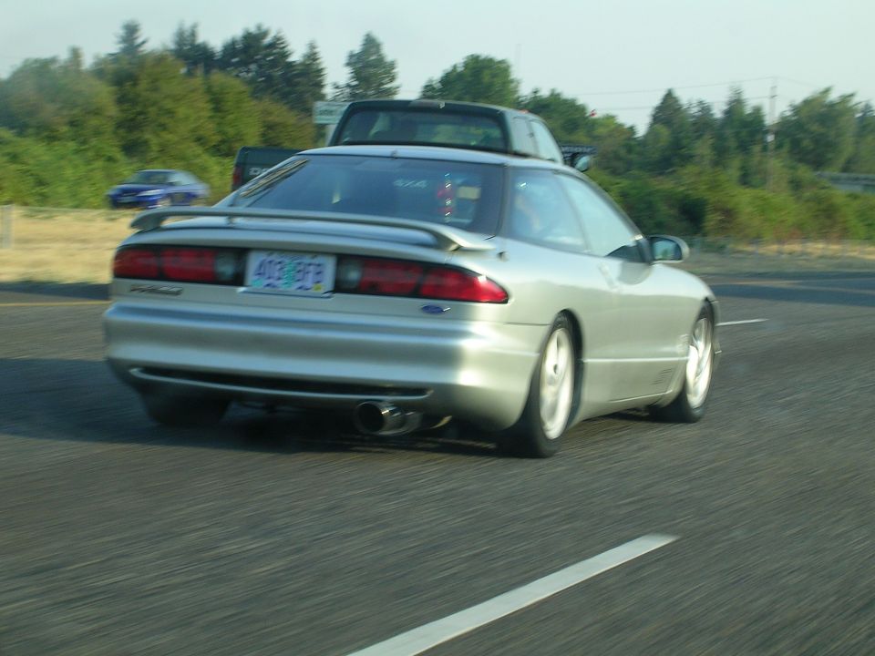 Silver Ford Probe rolling shot from rear with spoiler and large exhaust tip