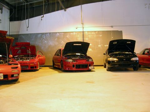 1996 Ford Probe - A red 1996 Ford Probe is parked indoors with its hood open, alongside other vehicles.