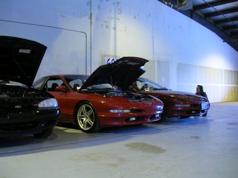 1996 Ford Probe - Three Ford Probes are lined up indoors, two red and one black, all with hoods open.