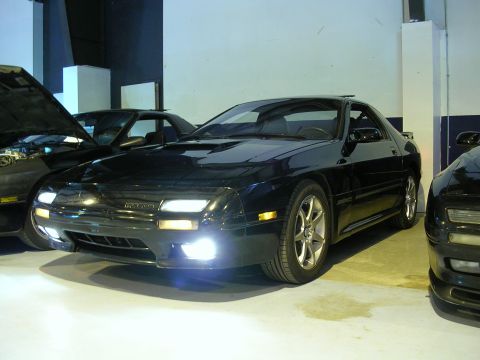 1996 Ford Probe - A dark-colored Mazda RX-7 is parked in a garage with other vehicles.