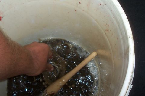 1994 Ford F-150 - Hand stirs murky liquid in a bucket, with a wooden stick visible.
