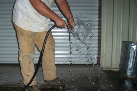 1994 Ford F-150 - Water sprays from a hose in front of a closed garage door, with a metal trash can nearby.