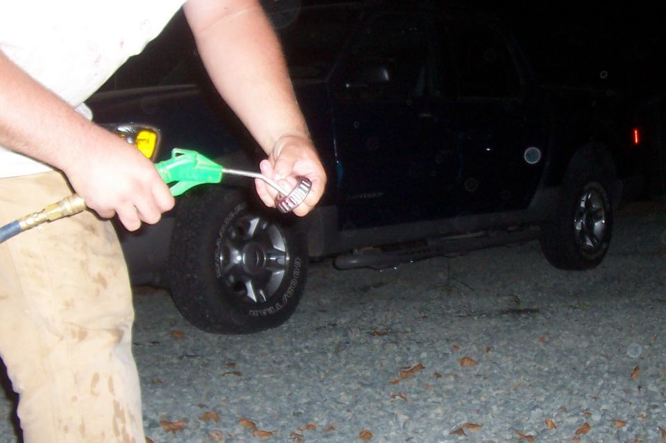 Dark colored SUV side view, person cleaning a metal bearing with an air gun