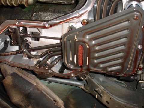 1993 Ford Taurus - Close-up view of a transmission pan and filter, showing reddish fluid and internal components.