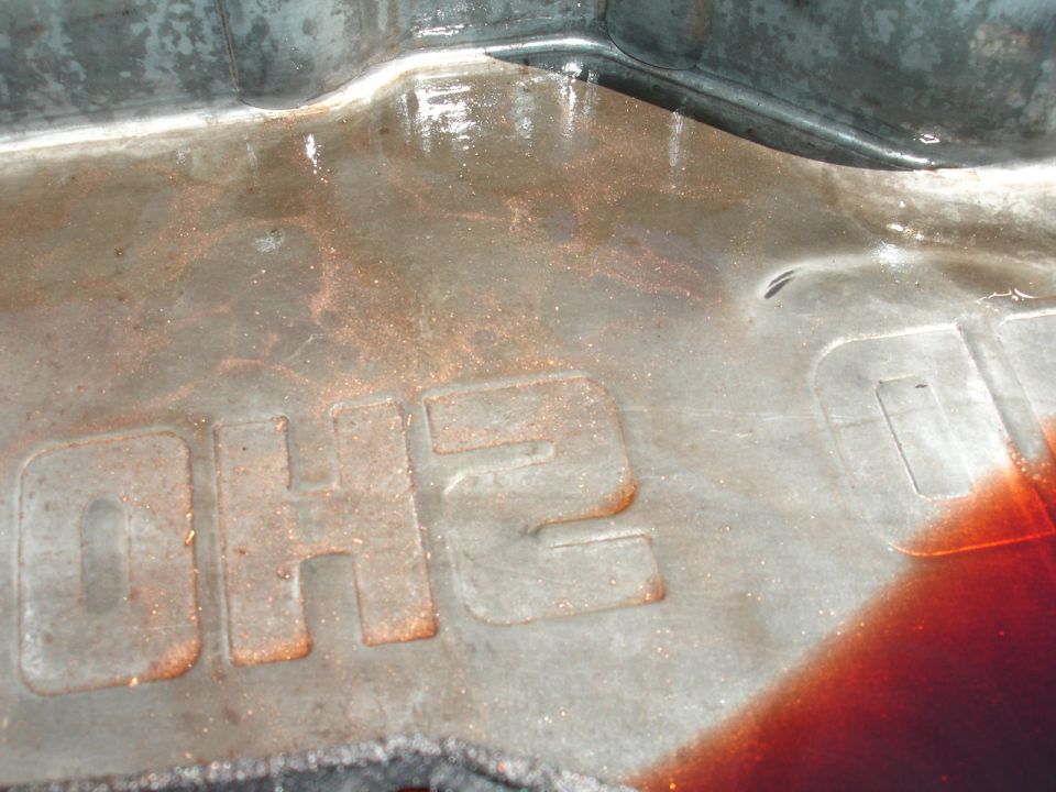 Close-up of metal part with embossed text 'OH2' and reddish fluid