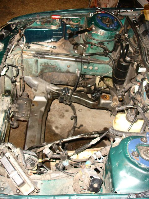 1993 Ford Taurus - Engine bay of a green vehicle, showing the subframe, transmission, and motor components during repair.