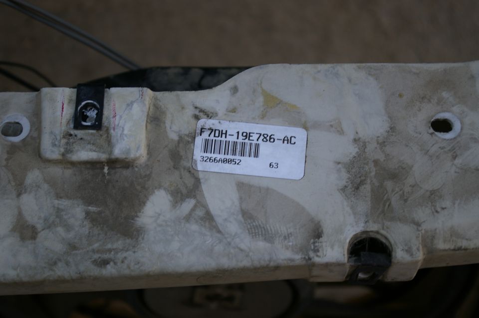 Close-up of a white plastic part with a label that reads F7DH-19E786-AC and a barcode