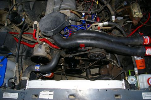 1986 Ford Bronco - A close-up view of a vehicle's engine compartment, showing various hoses, wires, and mechanical components.