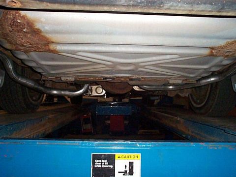 1991 Ford Crown Victoria - The underside of a vehicle shows dual exhaust pipes and significant rust on the frame, indicating potential structural wear.