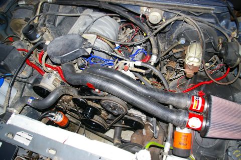 1986 Ford Bronco - A close-up view of a vehicle's engine compartment, showing various hoses, wires, and aftermarket air filters.