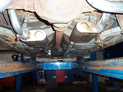 1991 Ford Crown Victoria - Underside of a vehicle on a lift, focusing on the exhaust system and drivetrain components.