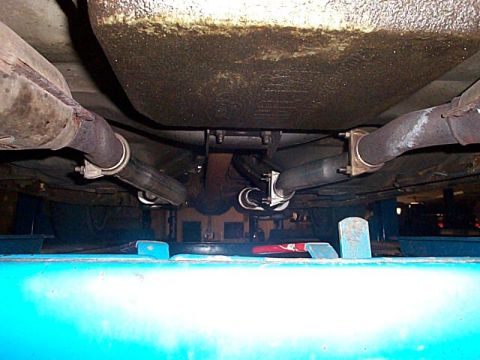 1991 Ford LTD Crown Victoria - Underbody view of a car on a blue drive-on lift showing a custom true dual exhaust: two catalytic converters feeding welded-in mufflers wit…