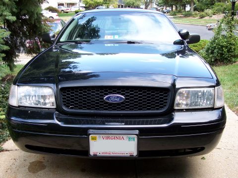 2001 Ford Crown Victoria - Front view of a black 2001 Ford Crown Victoria police car, showing its grille and headlights.
