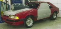 1990 Ford Mustang - A red and silver 1990 Ford Mustang is shown in a garage with a large air intake scoop and unfinished body panels.