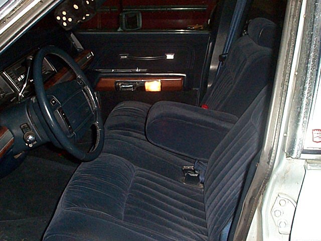 Blue cloth bench-seat interior of a full-size sedan viewed through the driver's door