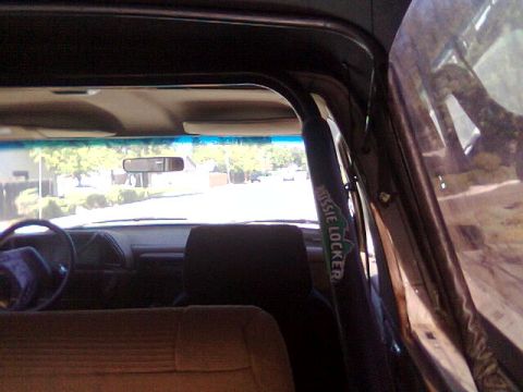 1989 Ford Bronco - The interior of a vehicle is visible, including a roll bar with text and a view of the dashboard and steering wheel.