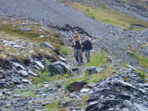 2000 Ford E350 - Two hikers ascend a steep, rocky slope with sparse vegetation.