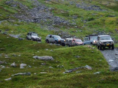 2000 Ford E350 - A group of off-road vehicles navigates a challenging terrain on a cloudy day.