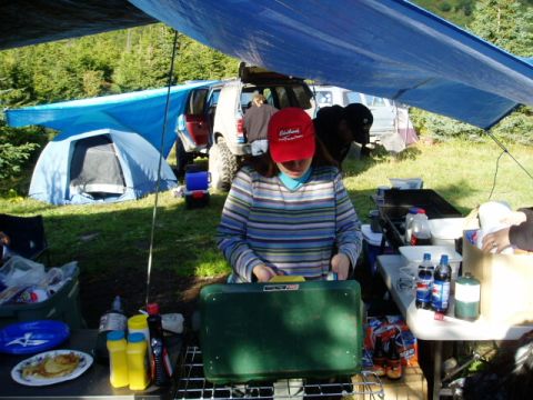 2000 Ford E350 - A group enjoys a camping trip with a tent set up and a meal being prepared outdoors.