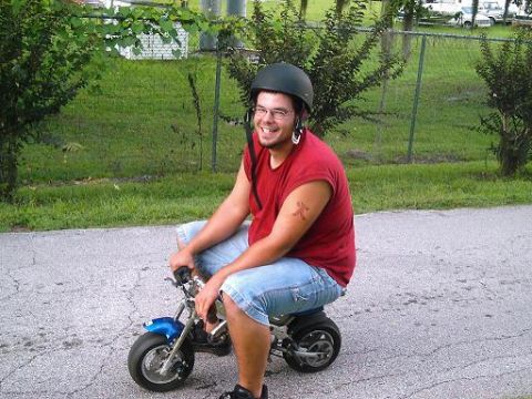1986 Ford Bronco - A man wearing a helmet and glasses rides a blue mini bike on a paved surface.