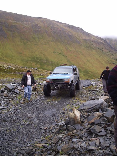 2000 Ford E350 - A modified SUV navigates a challenging rocky terrain on a mountain pass.