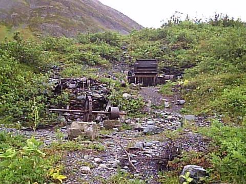 2000 Ford E350 - Overgrown landscape with remnants of old mining equipment, suggesting a historical site.