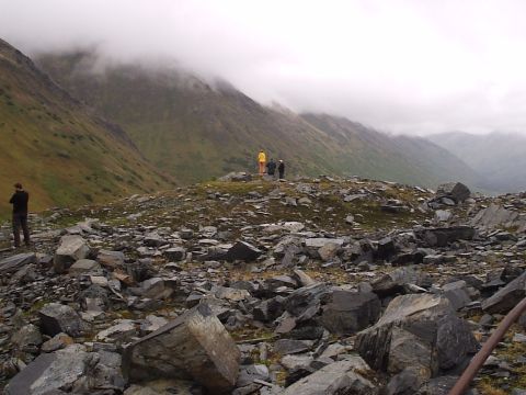 2000 Ford E350 - A group of people stand on a rocky outcrop, overlooking a vast mountain range shrouded in mist.