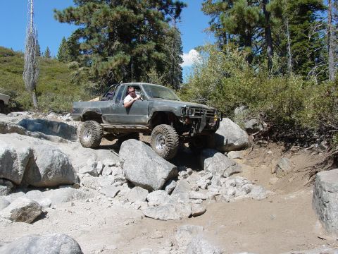 1986 Ford Bronco - A modified truck tackles a challenging off-road course with large boulders.