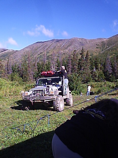 2000 Ford E350 - A modified Jeep Wrangler is parked in a mountainous, wooded area with people around it.