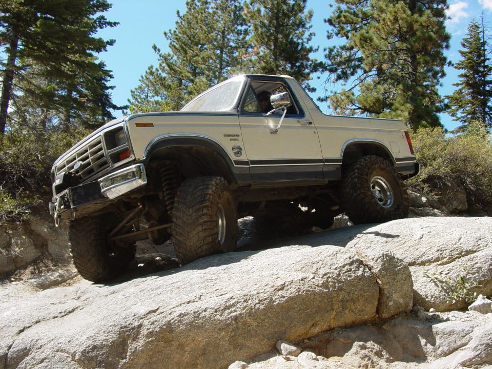 Tan Ford Bronco with off-road tires climbing rocks