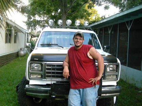 1986 Ford Bronco - A man poses in front of a white pickup truck with off-road lights mounted on the roof.